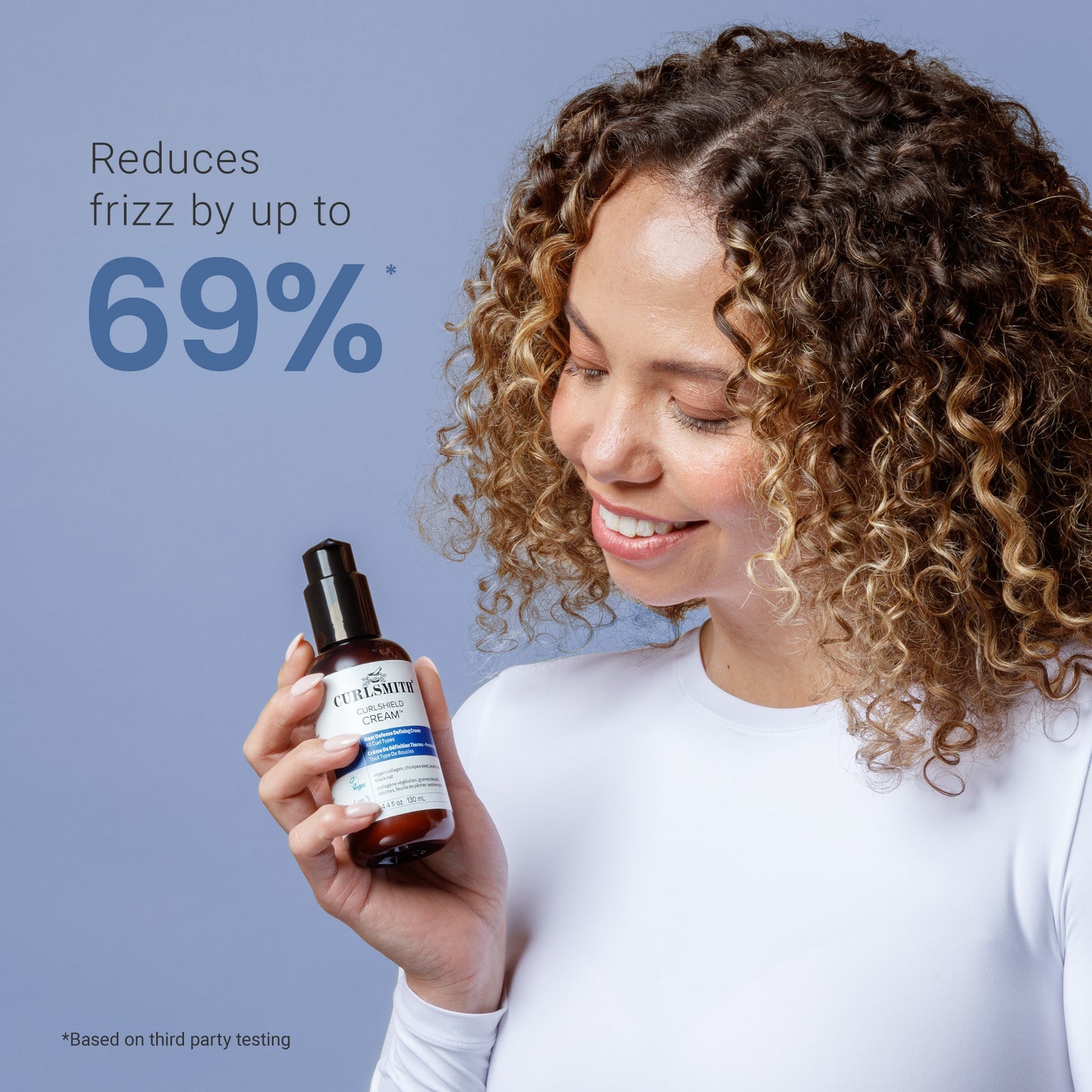 Woman holding a bottle of hair product with text claiming to reduce frizz by up to 69% on a blue background.