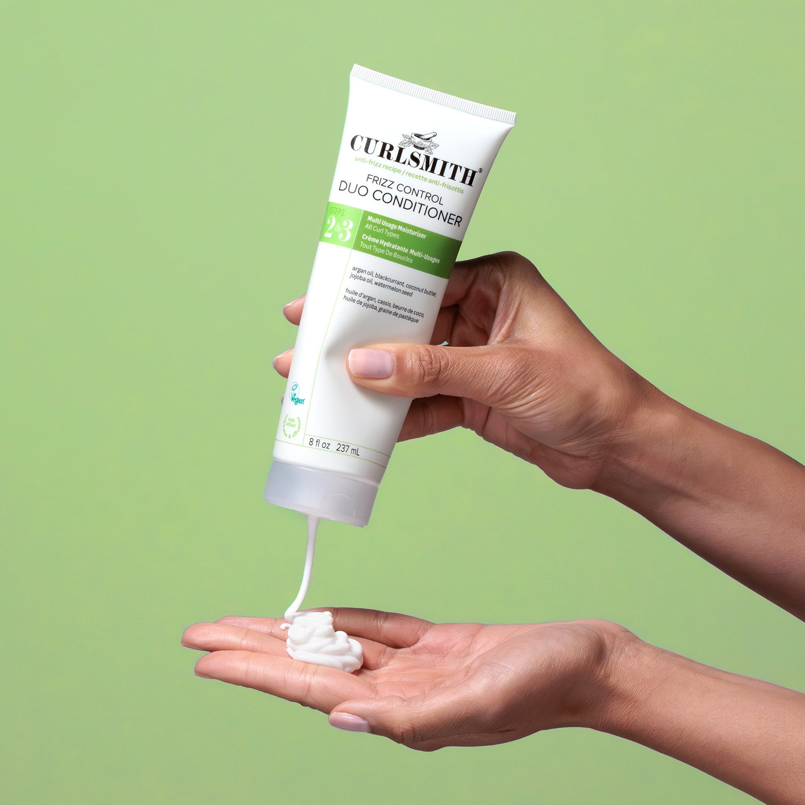 Curlsmith hair care product being applied to a hand against a green background