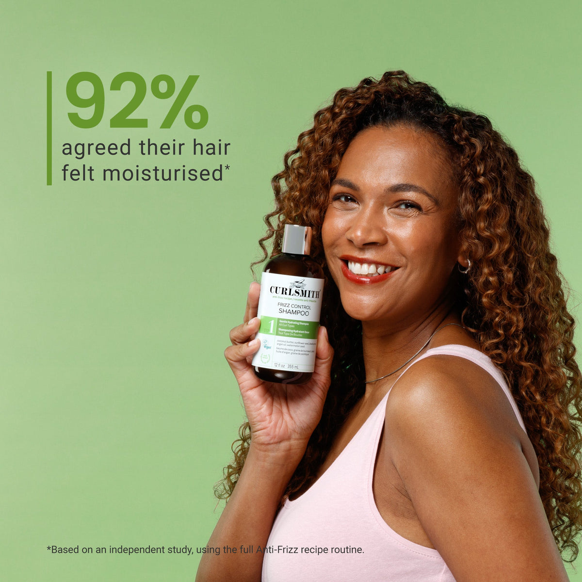 Woman holding a bottle of Curlsmith frizz control shampoo with a green background and text about hair moisturization.