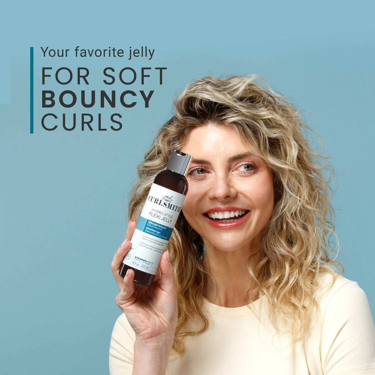 Woman holding a bottle of hydro style flexi jelly hair product with text about soft bouncy curls on a blue background