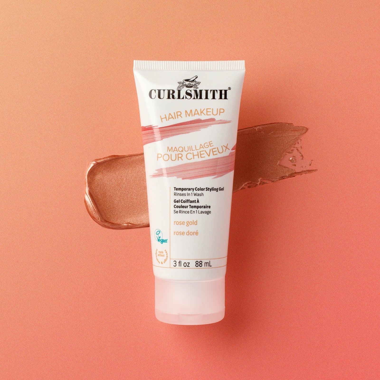 Curlsmith rose gold hair makeup tube on a peach background