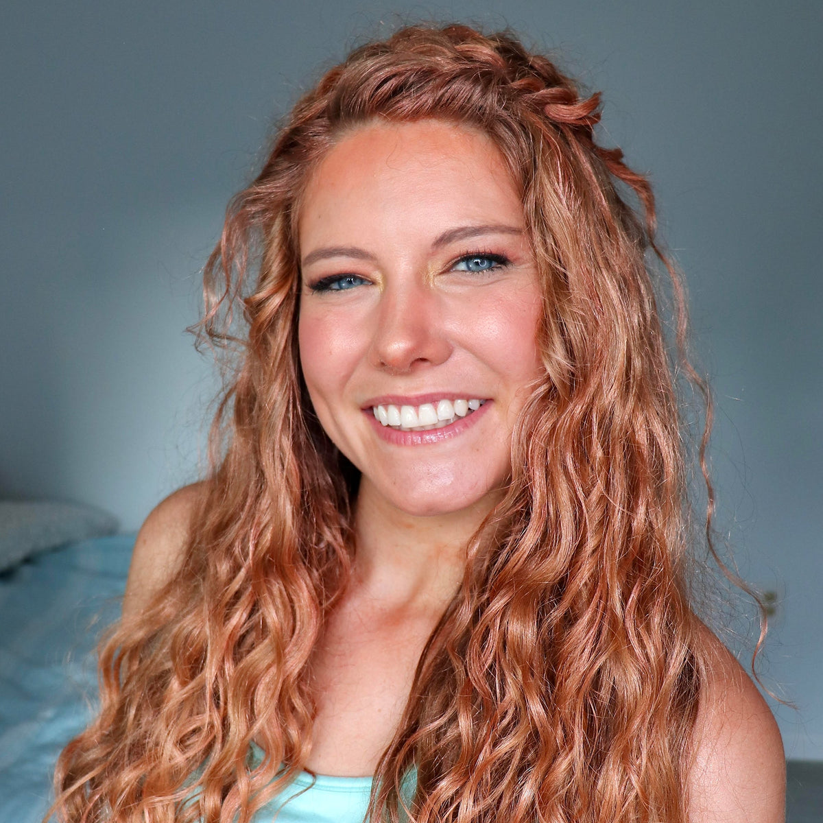 Woman with long, wavy red hair smiling against a neutral background