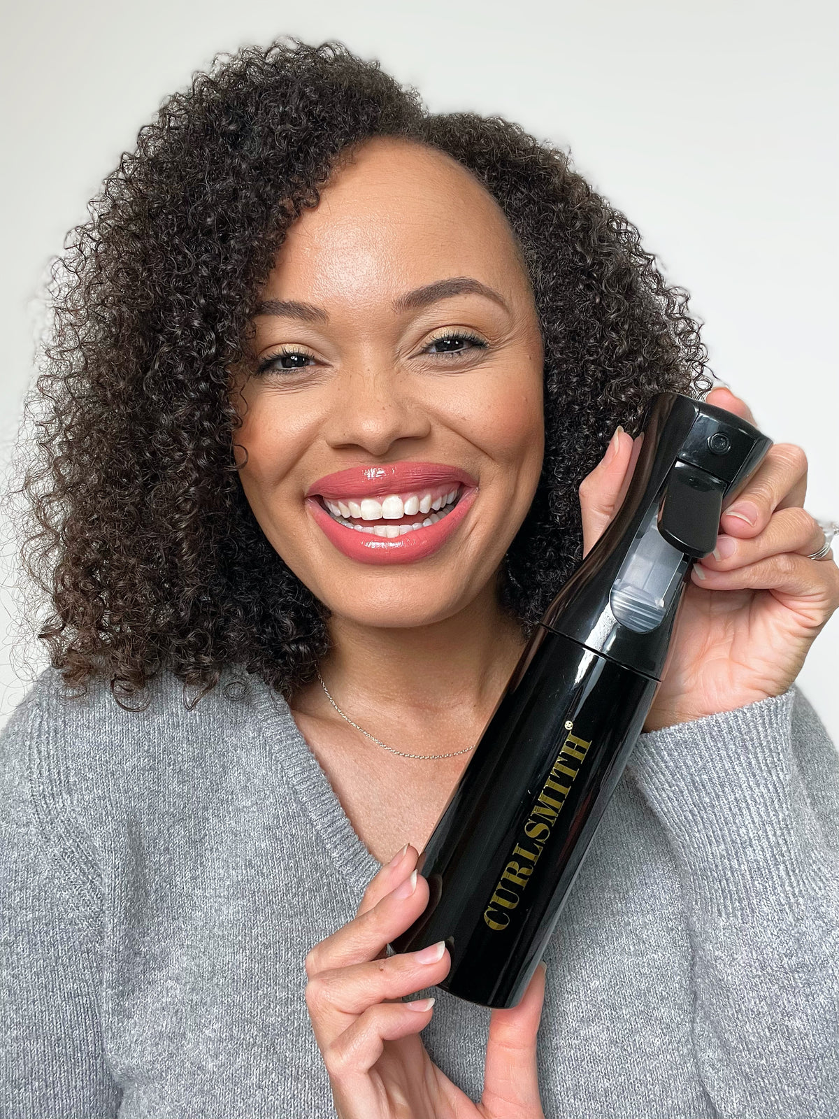 Coily haired woman holding black spray bottle