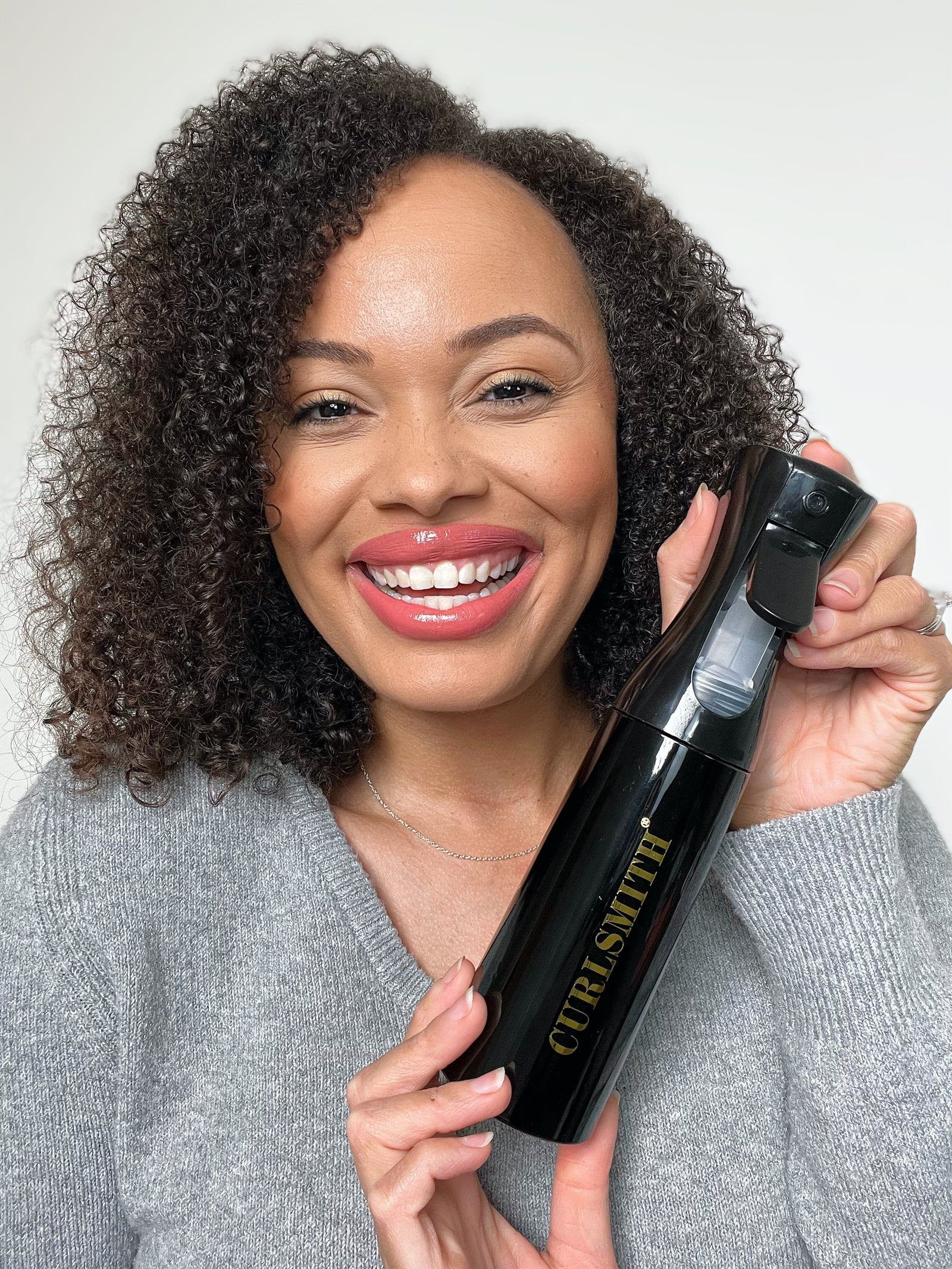 Coily haired woman holding black spray bottle