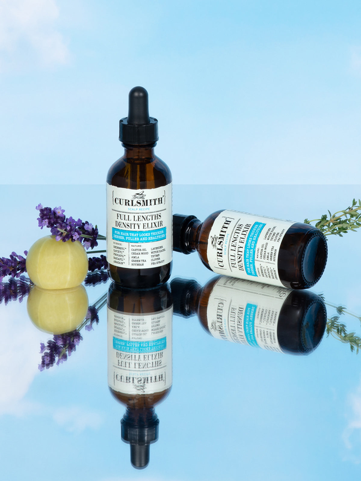 Curlsmith hair care products with lavender flowers on a reflective surface
