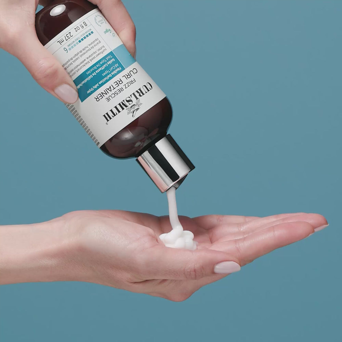 Hand squeezing Frizz Rescue Curl Retainer cream out on other hand