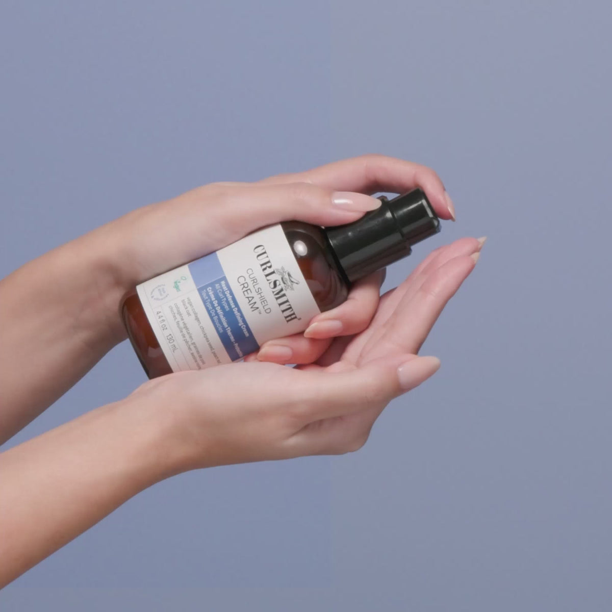 Hand pumping Curlshield Cream into other hand.