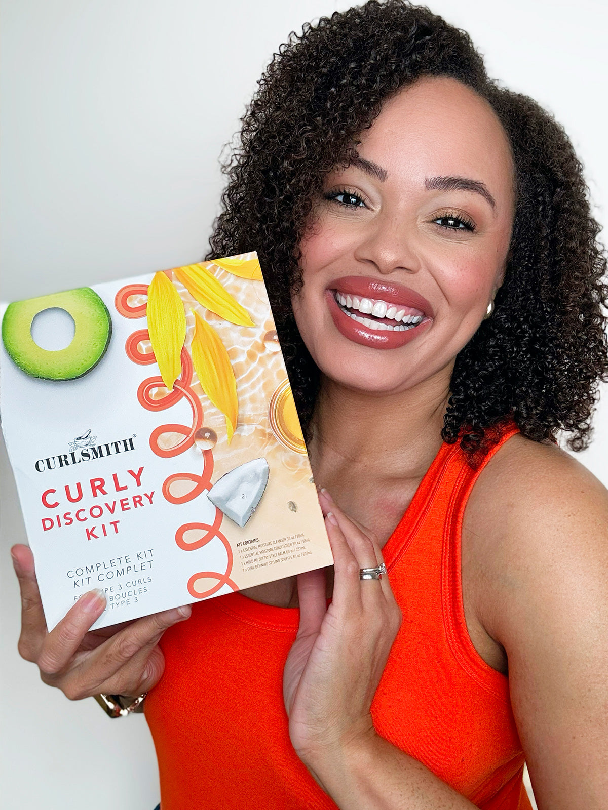 Curly woman holding the curlsmith curly discovery kit on white background