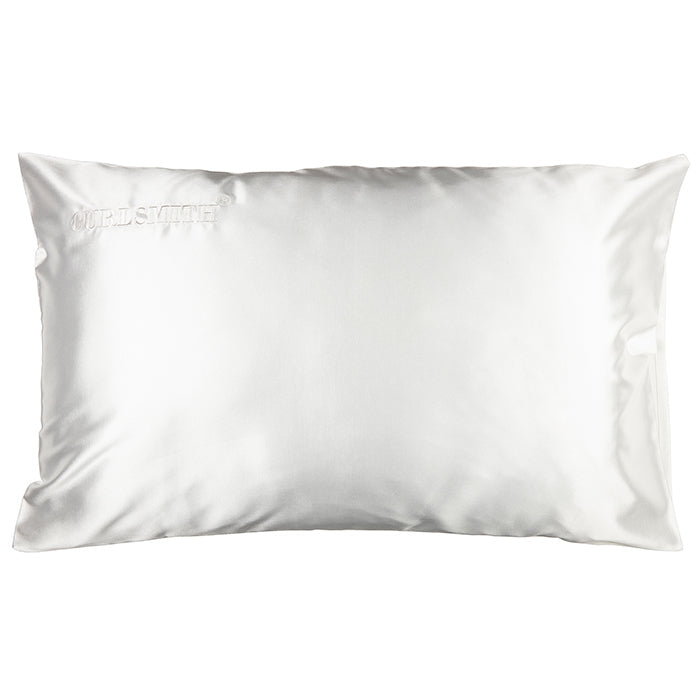 A white satin pillowcase on a pillow, with a subtle sheen.