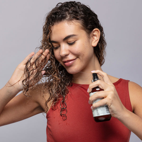 Woman with curly hair in front of gray background