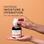Person holding a jar of Curlsmith Curl Conditioning Oil-in-cream with cream on fingers against an orange background