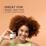 Woman with coily hair holding a jar of Curlsmith Curl Conditioning Oil-in-cream hair product against an orange background