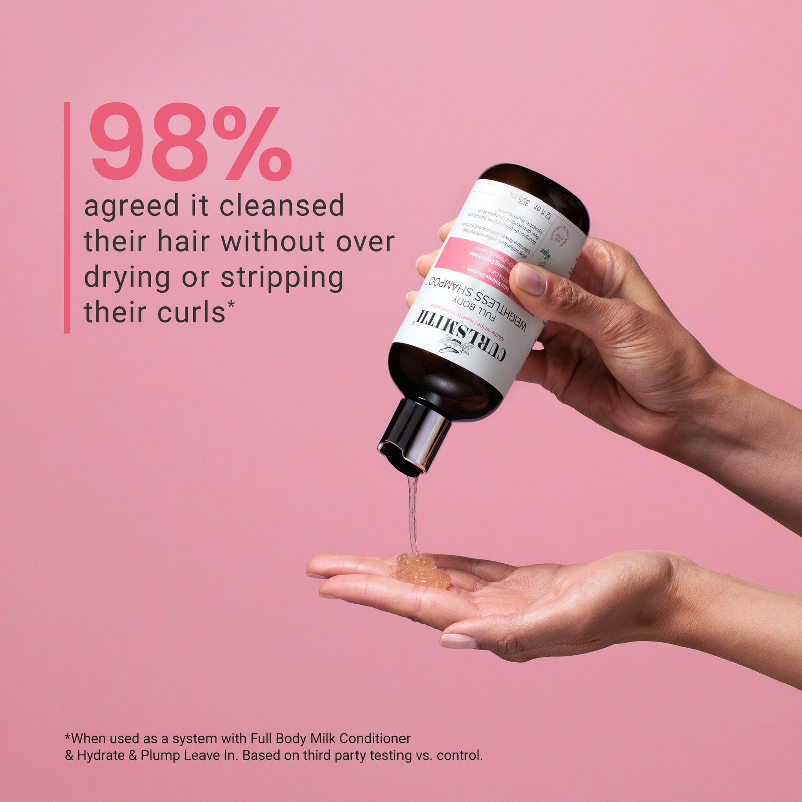Bottle of Curlsmith Full Body Weightless Shampoo being poured onto a hand with text on a pink background