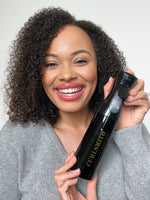 Coily haired woman holding black spray bottle