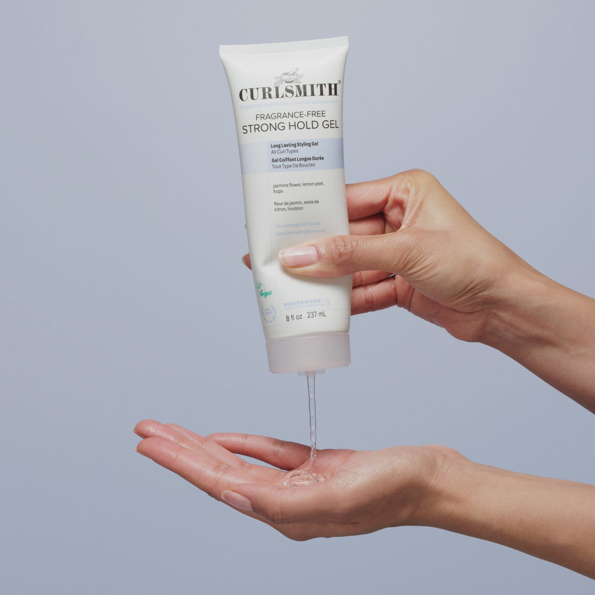 Hand squeezing Fragrance-Free Strong Hold Gel on hand below on a bright blue background