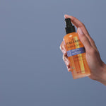 Hand holding Shake & Shine bottle and spraying it.