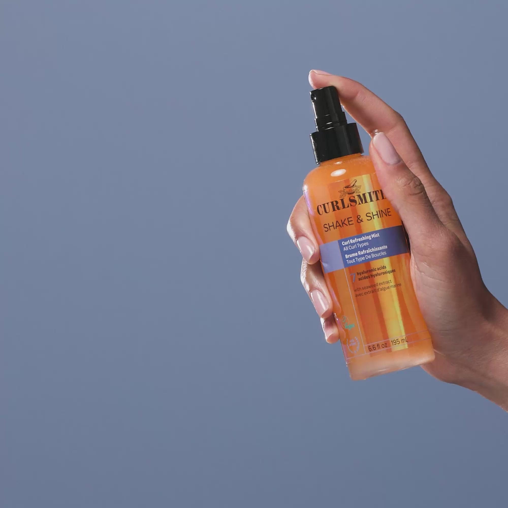 Hand holding Shake & Shine bottle and spraying it.