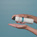 Person using Curlsmith Invincible Volume Mousse on a blue background