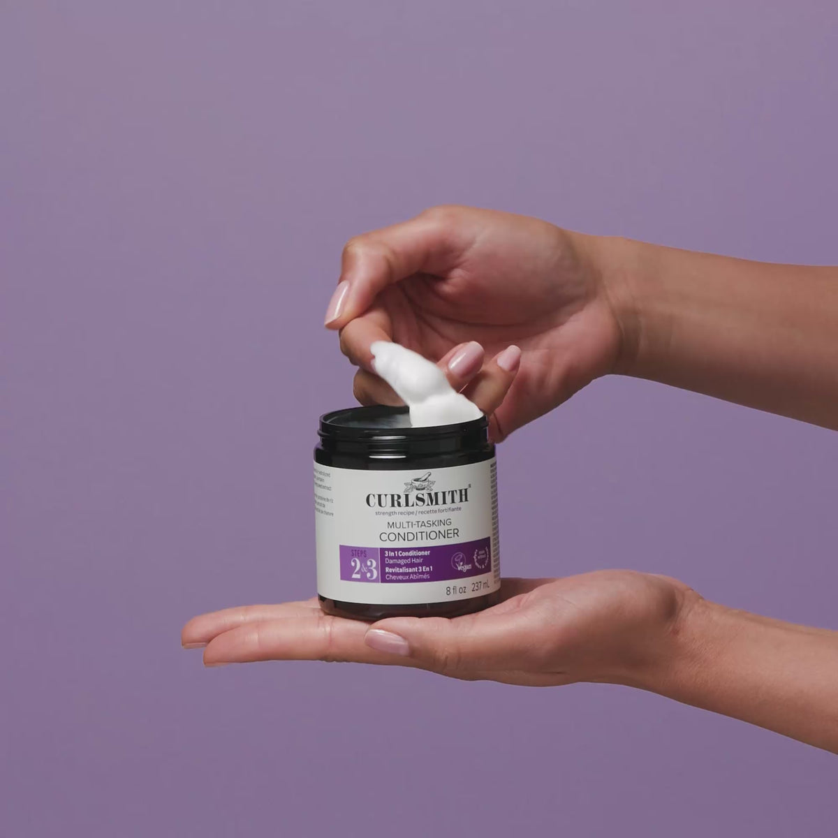 Hands dipping into multi-tasking conditioning cream on purple background