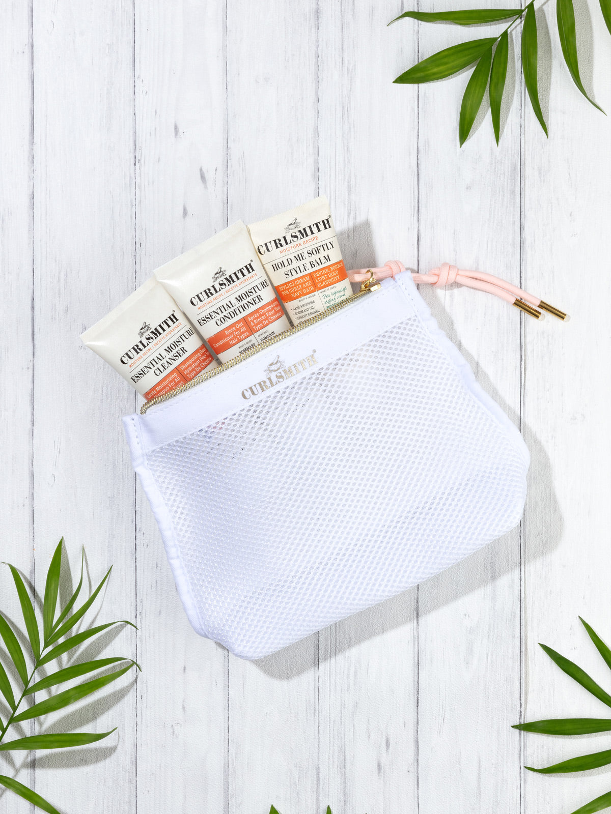 A clear mesh travel bag with three orange and white colored tubes labeled 'CURLSMITH'.