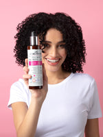 Woman holding Full Body Volumizing Lotion against pink background 