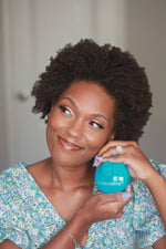 Woman holding a blue scalp massager with the brand name Curlsmith inscribed on it.