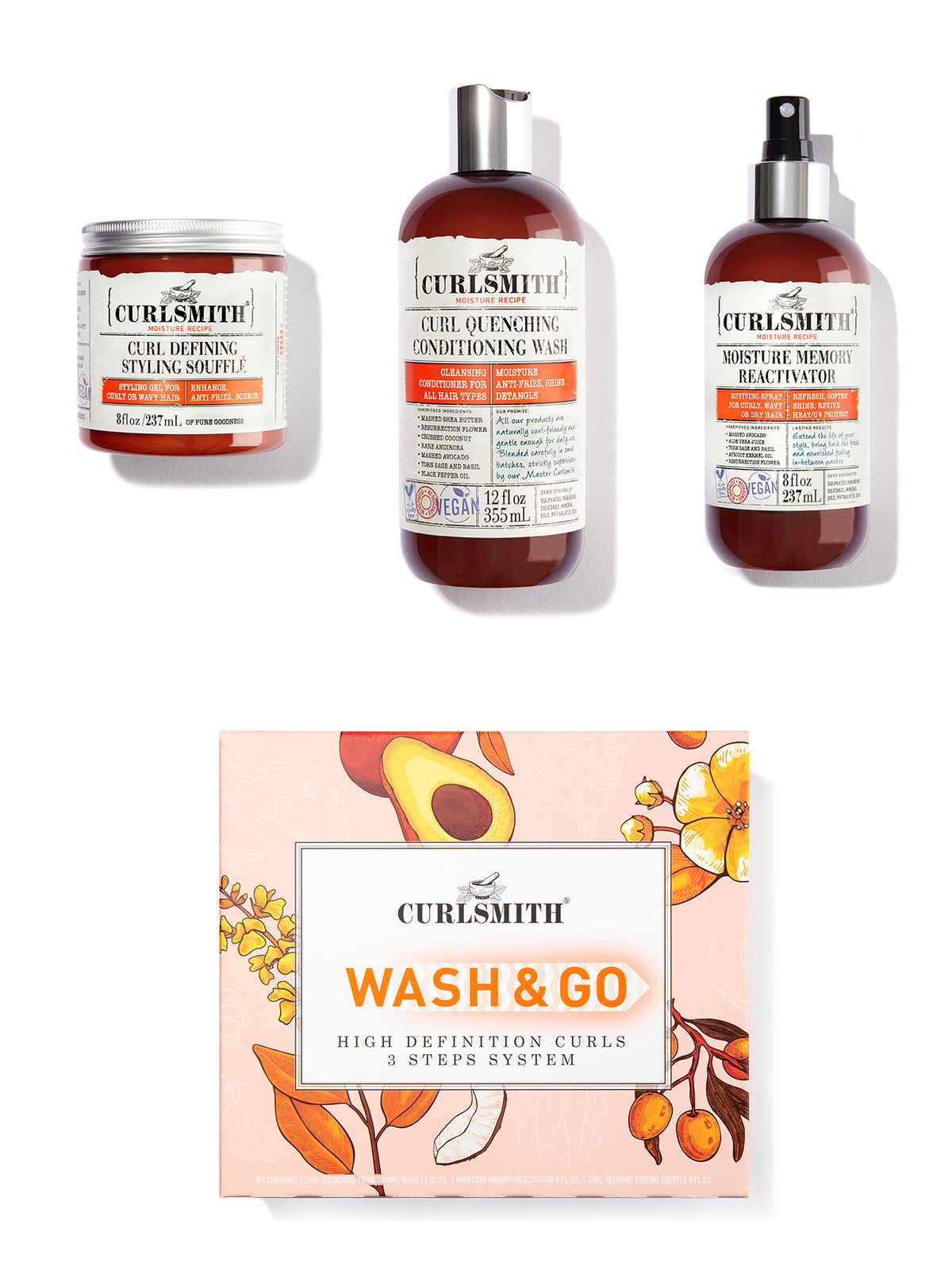 A set of hair care products from Curlsmith including a jar, bottle, and spray can with orange labels, along with a 'Wash & Go' kit box featuring floral and fruit illustrations.