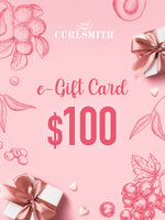 An e-Gift Card from Curlsmith featuring a $100 denomination, with decorative elements such as leaves and gift boxes in blue tones.